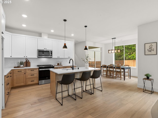 6719 NE 132nd St, Vancouver, WA 98686 - kitchen featuring appliances with stainless steel finishes, a sink, backsplash, light wood finished floors, and a breakfast bar area