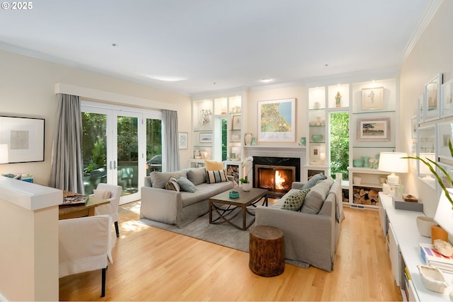 living room featuring ornamental molding, a premium fireplace, french doors, and light wood-type flooring
