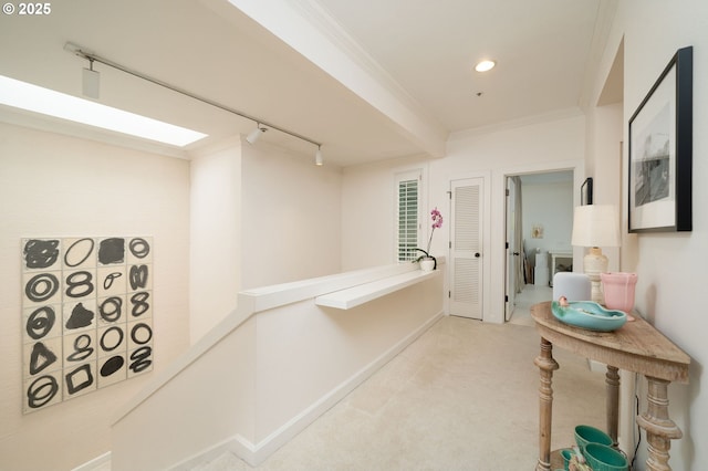 corridor featuring ornamental molding, light colored carpet, rail lighting, baseboards, and recessed lighting