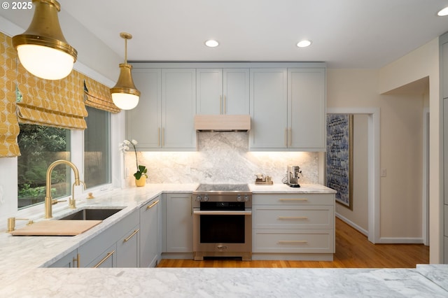 kitchen with high end stove, gray cabinetry, light wood finished floors, and recessed lighting