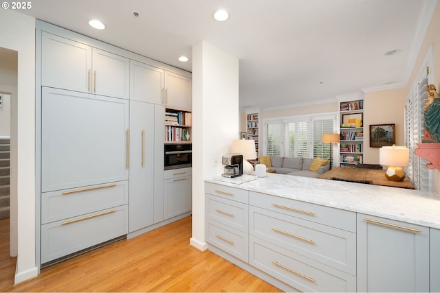 kitchen with light wood finished floors, light stone countertops, open floor plan, recessed lighting, and crown molding