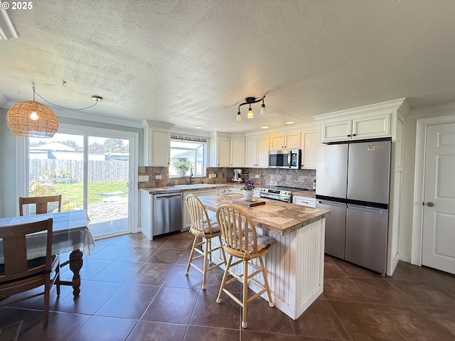 1206 Iris St, Brookings, OR 97415 - kitchen featuring appliances with stainless steel finishes, backsplash, a kitchen breakfast bar, dark tile patterned floors, and a sink