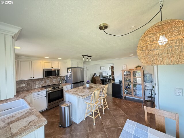 1206 Iris St, Brookings, OR 97415 - kitchen with stainless steel appliances, a center island, a sink, dark tile patterned flooring, and a breakfast bar area