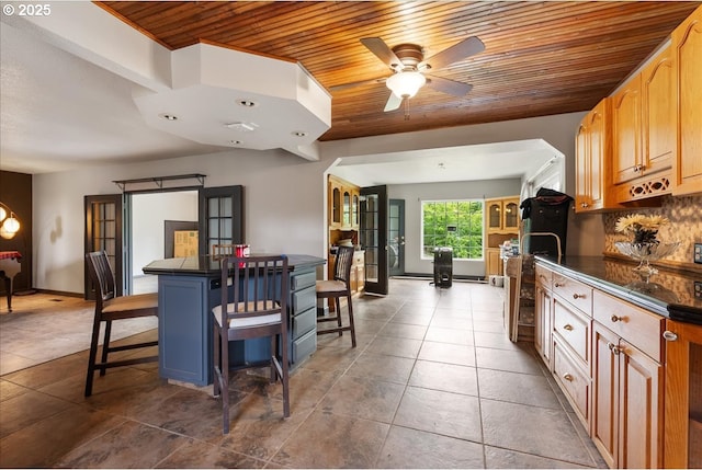 dining area featuring dark tile patterned flooring, baseboards, wooden ceiling, and ceiling fan