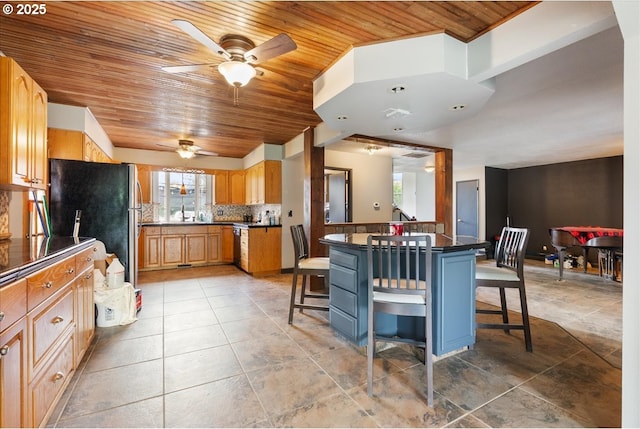 kitchen with a ceiling fan, dark countertops, tasteful backsplash, wooden ceiling, and a breakfast bar