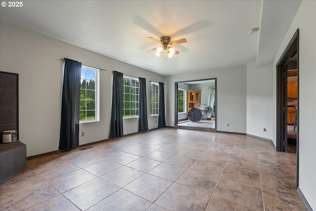 unfurnished living room with ceiling fan, visible vents, baseboards, and tile patterned flooring