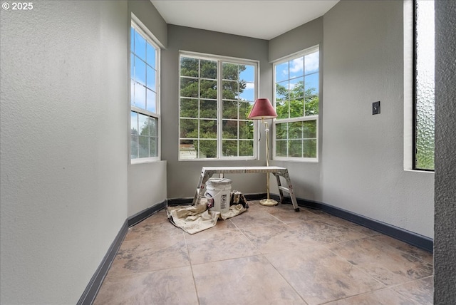 unfurnished room with a textured wall and baseboards