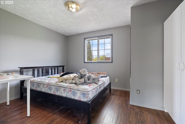 bedroom with baseboards, a textured ceiling, and wood finished floors