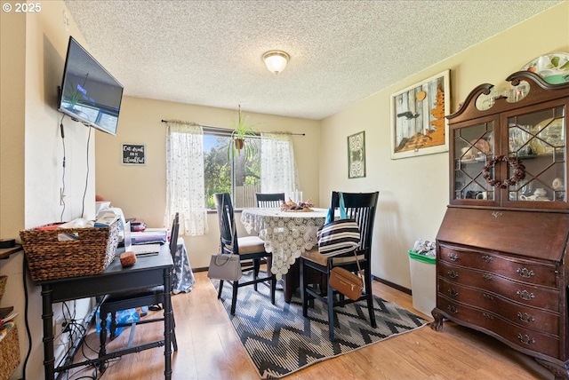dining room with a textured ceiling, baseboards, and wood finished floors