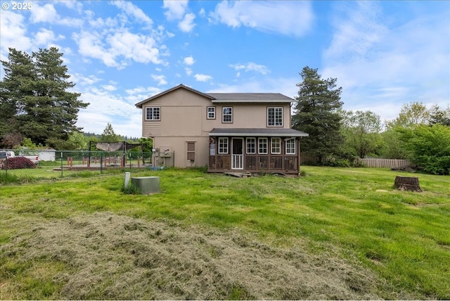 rear view of house featuring a yard, a deck, fence, and stucco siding