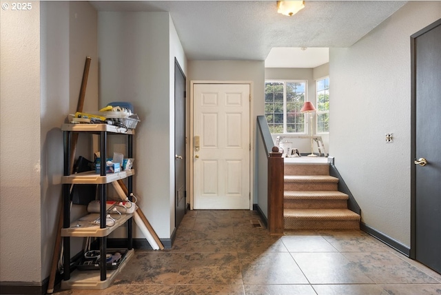 foyer with baseboards and a textured ceiling