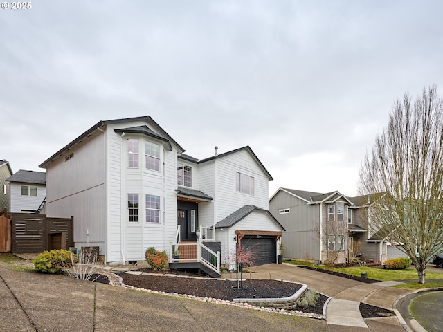 view of front facade featuring concrete driveway, an attached garage, and fence