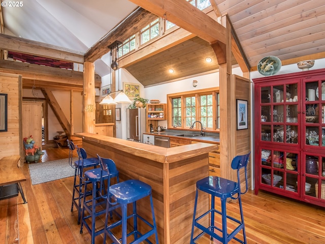 bar featuring lofted ceiling with beams, stainless steel appliances, hardwood / wood-style floors, and a sink