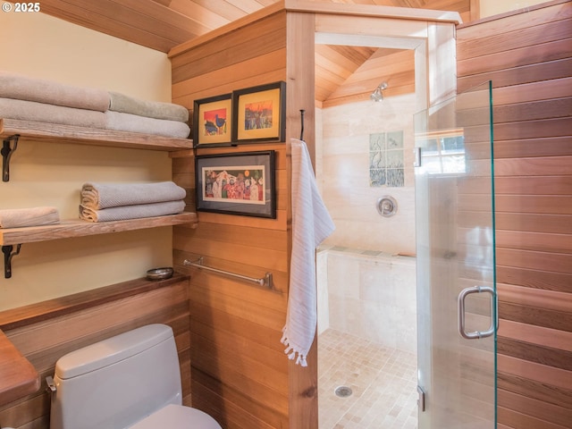 bathroom with wooden walls, toilet, and a stall shower