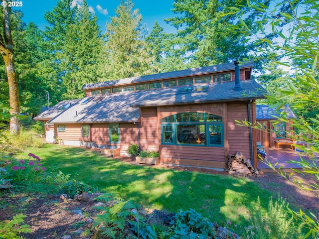 chalet / cabin featuring a front yard, a wooden deck, and a shingled roof