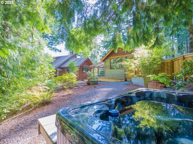 view of pool featuring an outdoor hot tub, fence, and a wooden deck