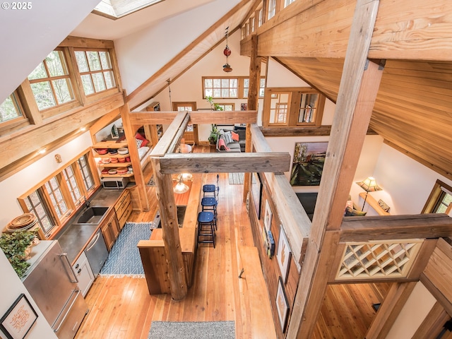 interior space featuring wood-type flooring, high vaulted ceiling, a healthy amount of sunlight, and a skylight