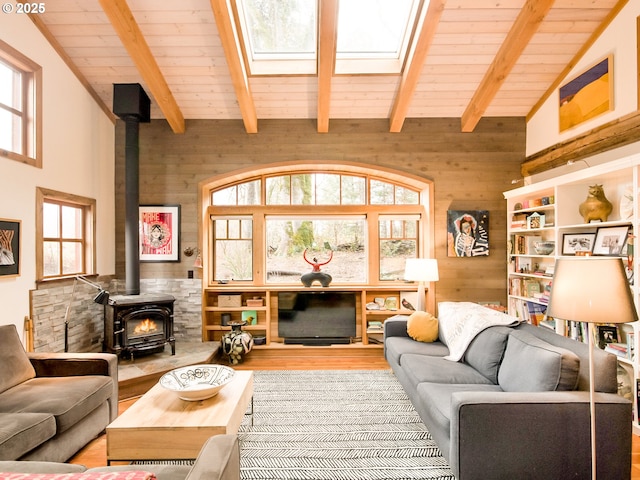 living area featuring wooden walls, wood finished floors, a wood stove, wood ceiling, and beamed ceiling