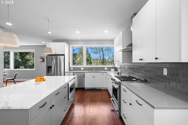kitchen with decorative backsplash, pendant lighting, appliances with stainless steel finishes, a center island, and a sink