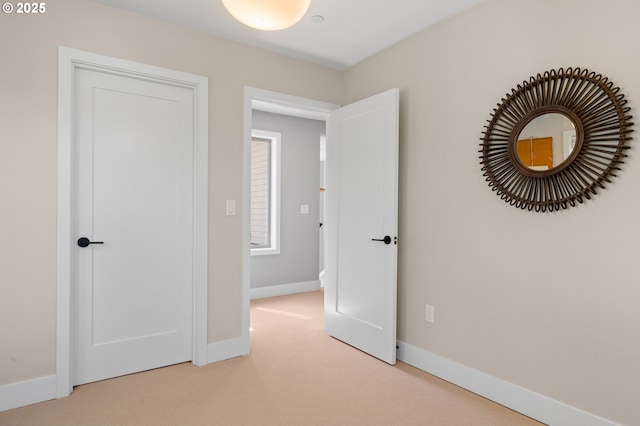 unfurnished bedroom featuring baseboards and light colored carpet