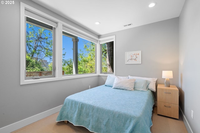 carpeted bedroom featuring baseboards, visible vents, and multiple windows