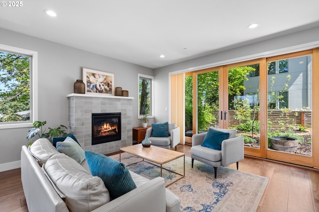 living room with wood finished floors, a healthy amount of sunlight, and a tile fireplace