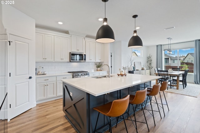4815 S 12th Cir, Ridgefield, WA 98642 - kitchen featuring stainless steel appliances, a sink, white cabinets, decorative backsplash, and light countertops