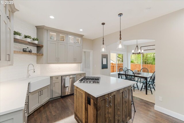 kitchen with decorative backsplash, dark wood-style floors, a chandelier, a sink, and appliances with stainless steel finishes