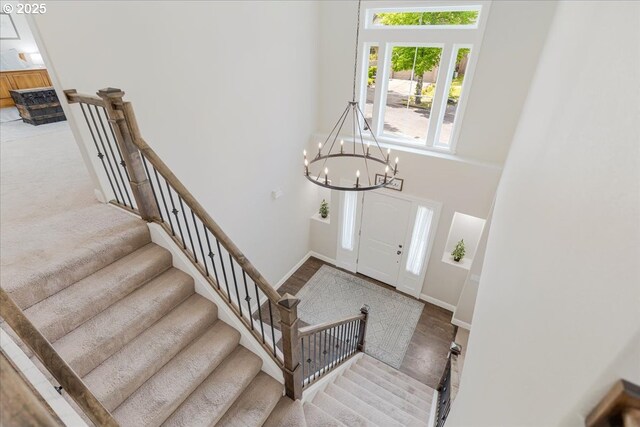 entrance foyer with baseboards, a notable chandelier, and stairway