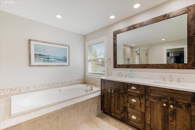 full bathroom featuring a sink, double vanity, a stall shower, and a bath