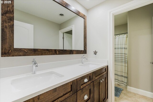 bathroom with a sink, baseboards, double vanity, and visible vents
