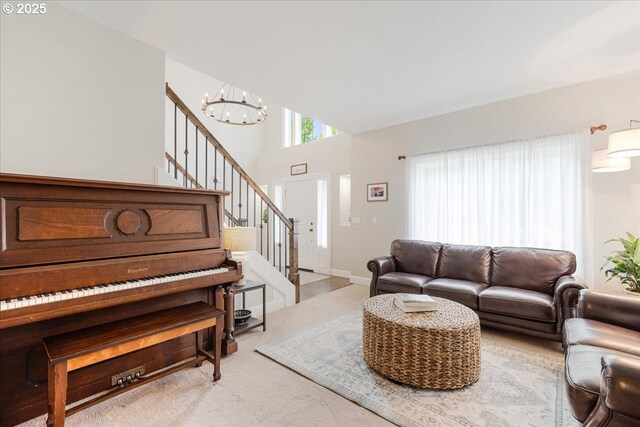 living room featuring carpet floors, stairs, a towering ceiling, and a notable chandelier