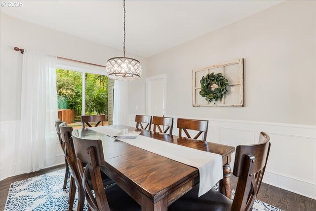 dining space featuring a wainscoted wall, wood finished floors, and a notable chandelier