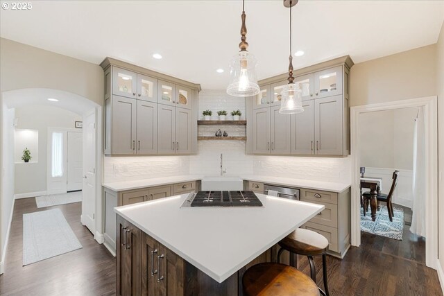 kitchen with a center island, a sink, dark wood-type flooring, and light countertops