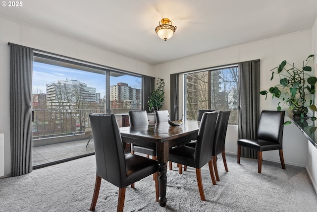 dining room with carpet floors, a view of city, and baseboards