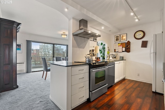 kitchen with stainless steel appliances, rail lighting, white cabinets, a peninsula, and exhaust hood