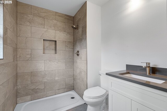 full bathroom with vanity, toilet, and tiled shower