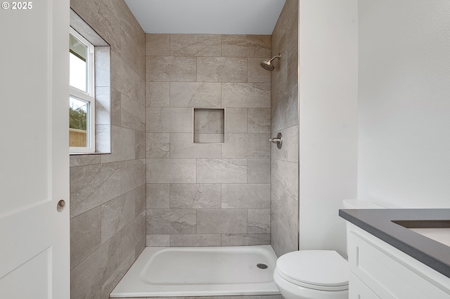 full bathroom featuring toilet, a tile shower, and vanity