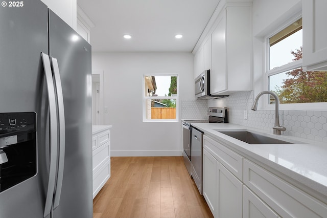 kitchen featuring a sink, appliances with stainless steel finishes, backsplash, and light countertops