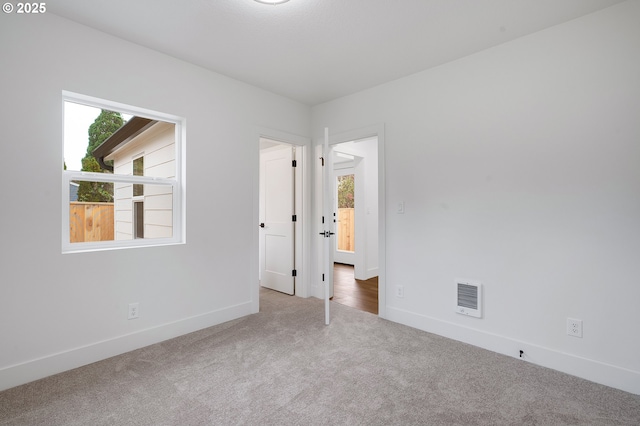 carpeted spare room with baseboards, visible vents, and a healthy amount of sunlight