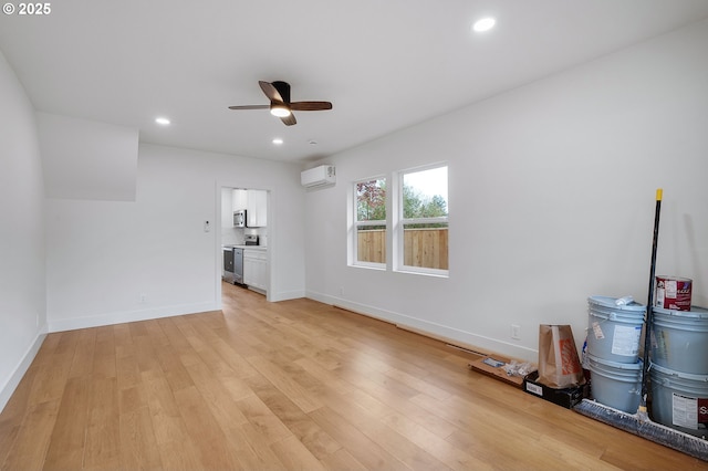 unfurnished living room with light wood-style floors, baseboards, recessed lighting, a wall unit AC, and a ceiling fan