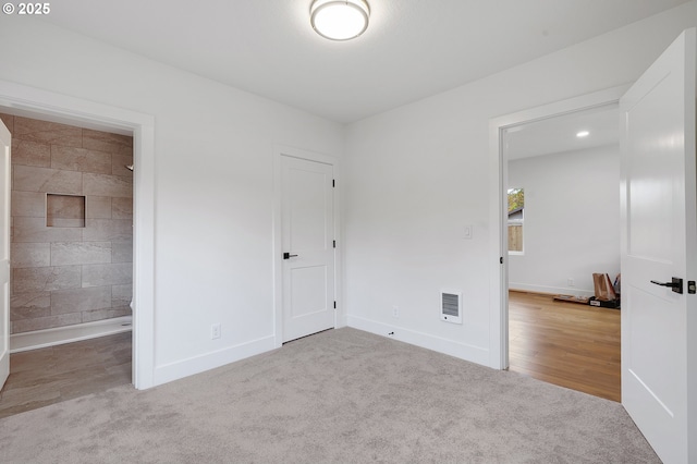 unfurnished bedroom featuring carpet floors, baseboards, and ensuite bathroom