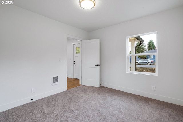 carpeted spare room featuring visible vents and baseboards