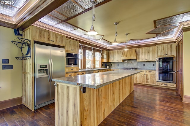 kitchen with dark hardwood / wood-style flooring, hanging light fixtures, premium range hood, and appliances with stainless steel finishes