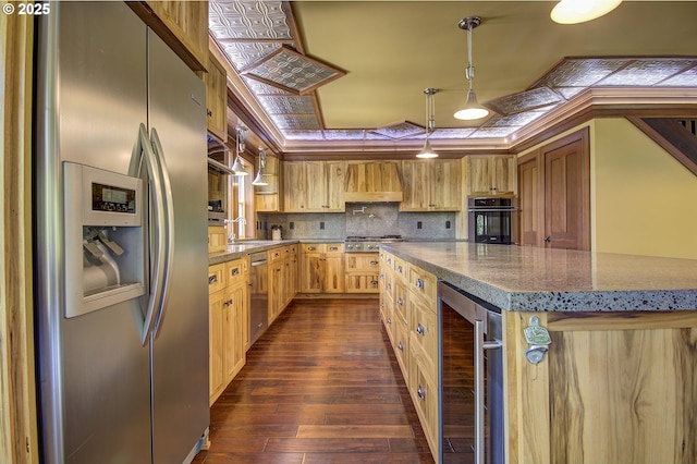 kitchen featuring appliances with stainless steel finishes, custom range hood, a kitchen island, decorative light fixtures, and beverage cooler