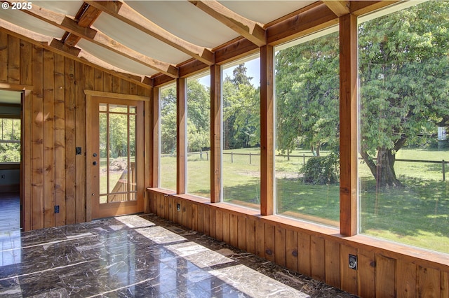 unfurnished sunroom with lofted ceiling with beams and a wealth of natural light