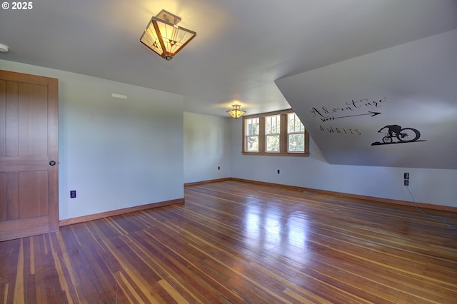 additional living space with dark wood-type flooring and vaulted ceiling