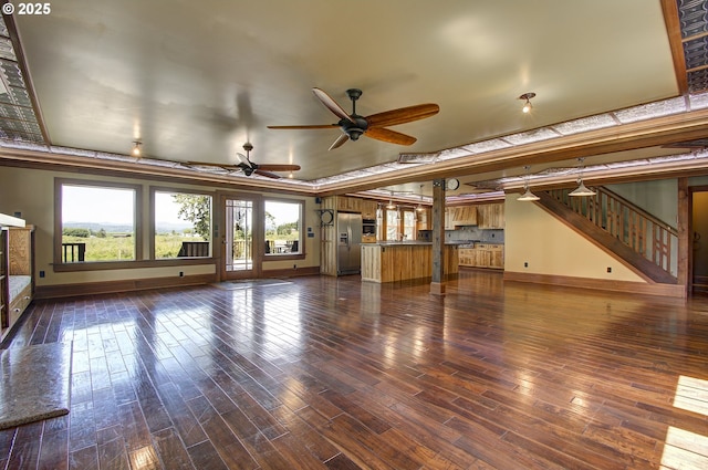 unfurnished living room featuring dark wood-type flooring, ceiling fan, and a raised ceiling