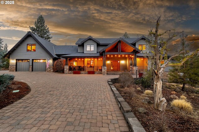 view of front of property with stone siding, a porch, decorative driveway, and an attached garage