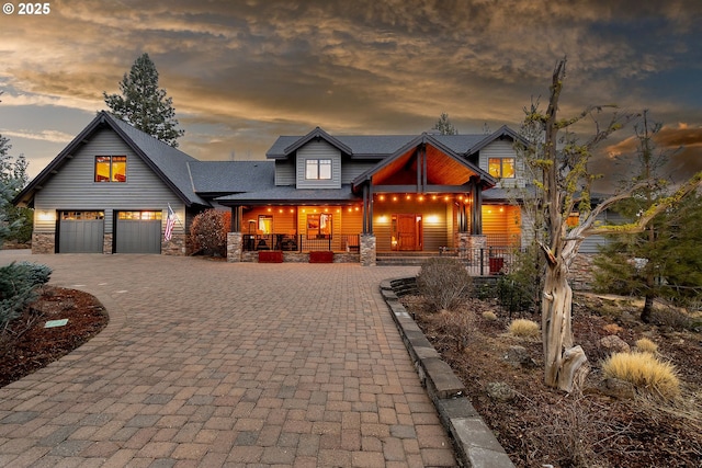 view of front of property with stone siding, a porch, decorative driveway, and an attached garage